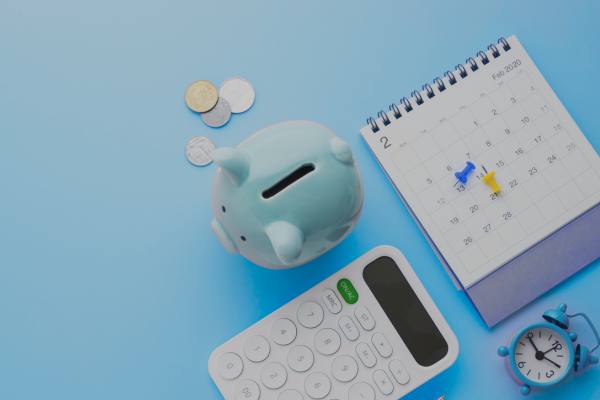 Calculator, notebook and piggy bank on a table