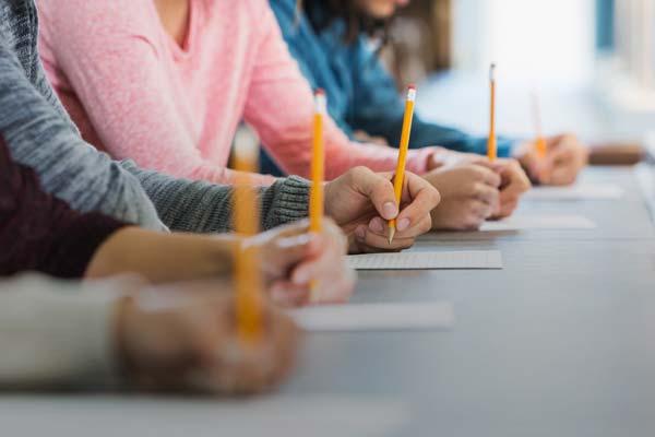 Hands writing on test papers