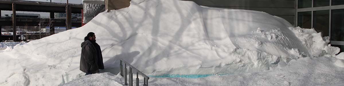 A man walking through huge snow piles A man walking through huge snow piles