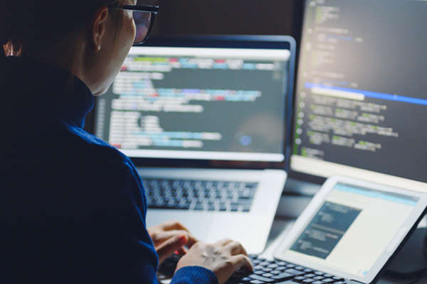 Women studying bright computer code on dark screens