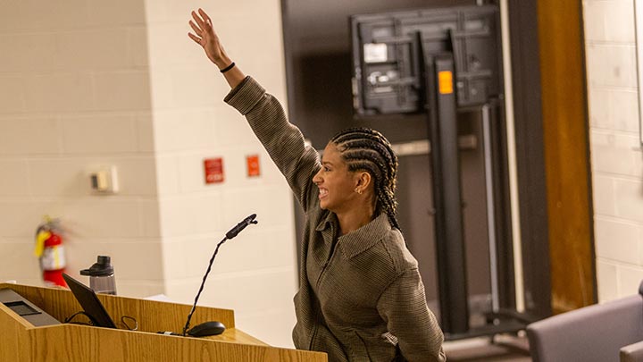 Student speaking at podium, hand raised