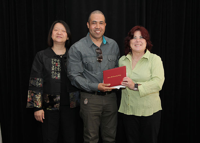 male student receives diploma from Toni and president eddinger 