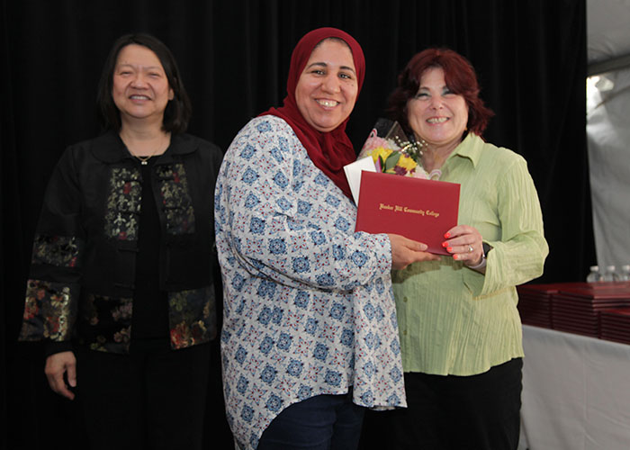 female student receives diploma from Toni and president eddinger 