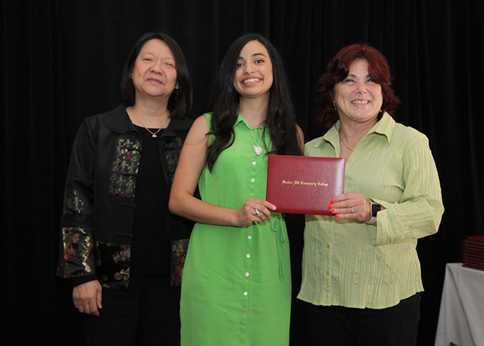 female student receives diploma from Toni and president eddinger 