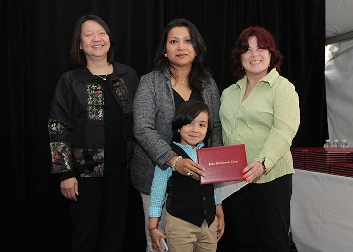 female student with her child receives diploma from Toni and president eddinger 