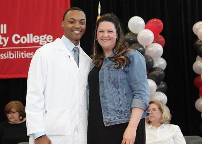 male student posing with faculty after receiving his pin