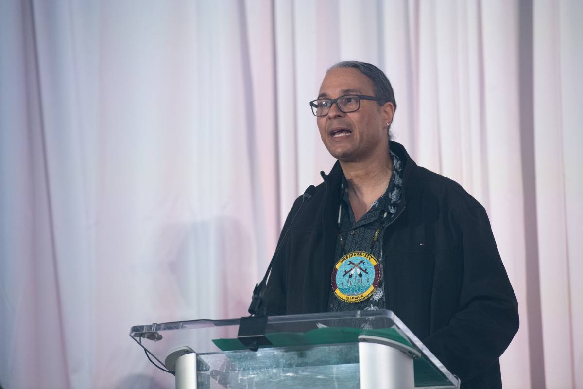 Larry Spotted Crow Mann speaking at podium