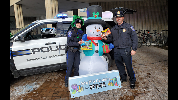 Two Cops Posing with Snowman infront of the Stuff the Toy Banner