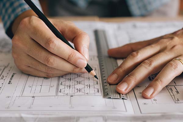 Person doing math with a pencil, paper and ruler