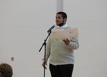 faculty member speaking at microphone on stage